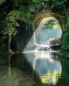 an image of a waterfall coming out of a tunnel in the forest with sunlight streaming through it