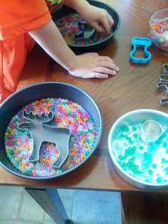 two pans filled with colorful sprinkles on top of a wooden table