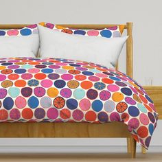 a bed with colorful comforters and pillows on it