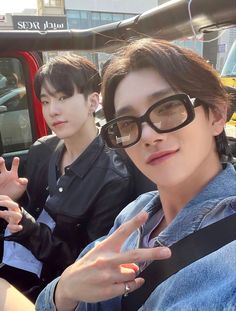 two young men sitting in the back of a truck with their fingers up and one pointing at the camera