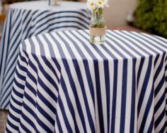 two vases filled with flowers on top of a blue and white striped table cloth