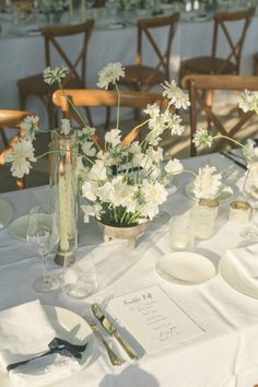 the table is set with white flowers and place settings