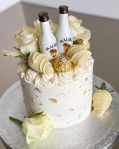 there is a cake that has two bottles on it and flowers around the bottom layer