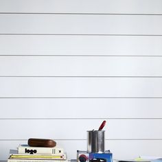 a table topped with books and other items on top of a hard wood floor next to a white wall