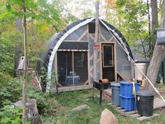 a tent in the woods with some trash cans