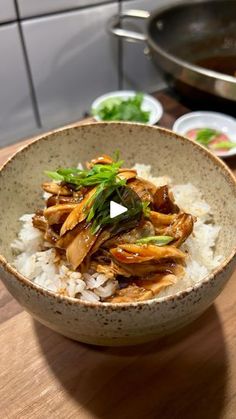 a bowl filled with rice and meat on top of a wooden table