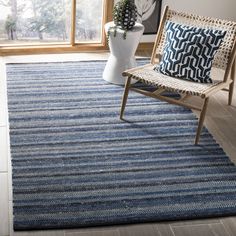 a blue and white area rug with a chair in front of a large window next to a potted plant