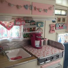 a kitchen with pink and white decor on the walls, stove top oven and sink