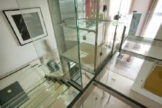 the inside of a house with glass walls and stairs leading up to the second floor