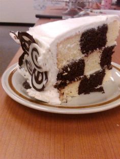 a slice of cake with white frosting and chocolate icing on a wooden table