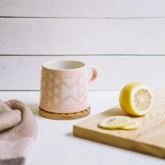 a cup with lemons on a cutting board next to a towel and a slice of lemon