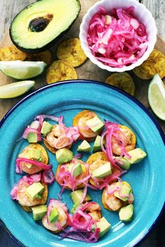 a blue plate topped with shrimp and avocado next to sliced up limes