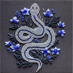 a white and blue beaded dragon on a gray background with flowers in the center