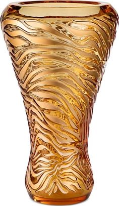 a golden vase with wavy lines on it's sides and bottom, sitting in front of a white background