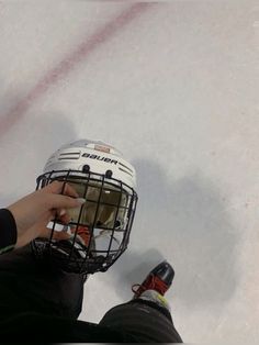 a person wearing a hockey helmet sitting on the ice with their foot in the goalie's net