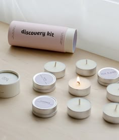 a group of white candles sitting on top of a wooden table next to a roll of paper