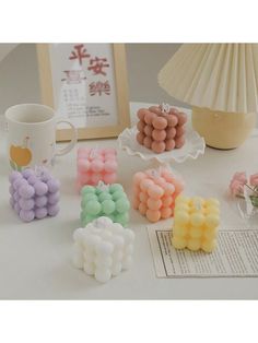 there are many small candies on the table next to a coffee cup and lamp