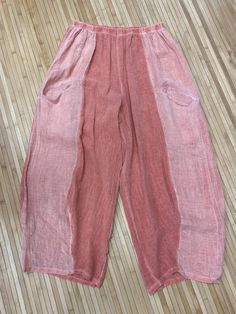 an old pair of pink pants sitting on top of a wooden floor next to a wall