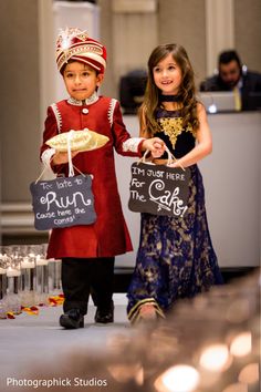 two young children are dressed in costumes and holding signs