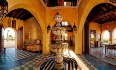 the inside of a house with an ornate fountain in the center and checkered tile flooring