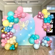 balloons and streamers are on the floor in front of an arch decorated with a butterfly