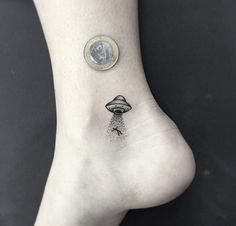 a small tattoo on the foot of a person with a coin in front of it