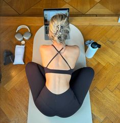 a woman sitting on a yoga mat with her back turned to the camera