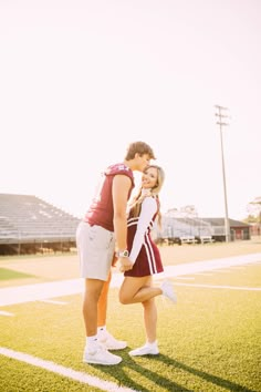 a man and woman standing on top of a field next to an empty football field