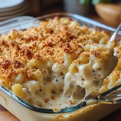 macaroni and cheese is being spooned into a casserole dish on a wooden table