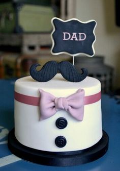 a white cake with a pink bow tie and a sign that says dad