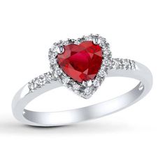 a white gold ring with a heart shaped ruby stone and diamonds on the band, set in