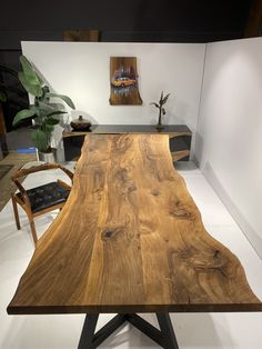 a large wooden table sitting on top of a white floor next to a black chair