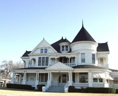 a large white victorian style house with black roof