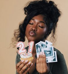 a woman holding two cupcakes with candles in her hands and photos on them