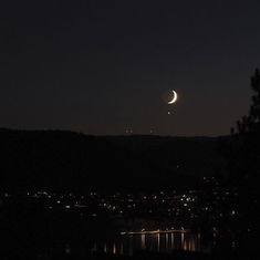 the moon and venus are seen over a city at night