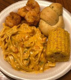 a white plate topped with pasta, corn and shrimp