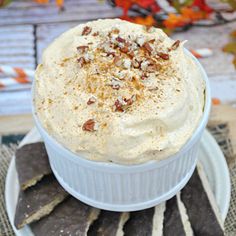 a white plate topped with a dessert covered in whipped cream and pecanse chips