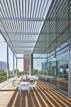 an outdoor dining area with wooden flooring and glass walls, overlooking the city skyline