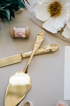 a table topped with gold colored utensils and flowers