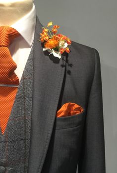 a suit with an orange tie and flower boutonniere