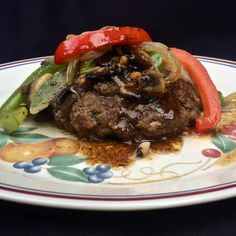 a plate topped with meat and vegetables on top of a floral design table cloth next to a fork