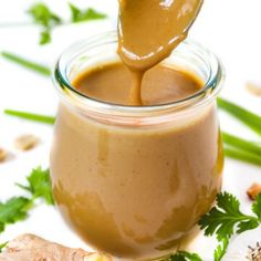 a spoon is pouring peanut butter into a jar