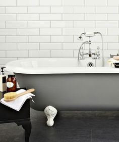 a bathroom with a claw foot bathtub and white brick walls, along with black flooring