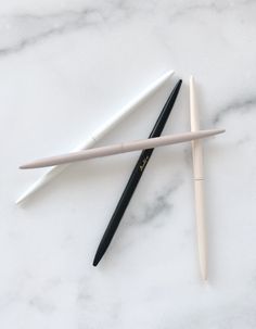 three different types of pens on a marble surface