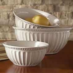 two white bowls with lemons in them on a wooden table next to napkins