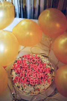 a birthday cake surrounded by balloons and confetti for someone's special occasion