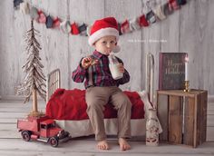 a little boy in a santa hat sitting on a bed drinking milk from a bottle