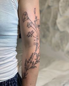 a woman's arm with flowers on it and a small tattoo in the middle