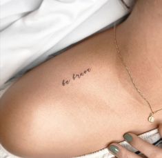 a woman's back with the word be brave tattooed on her left side ribcage