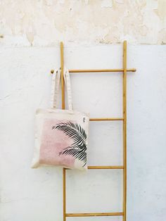 a tote bag hanging on a wall next to a towel rack with a palm leaf print